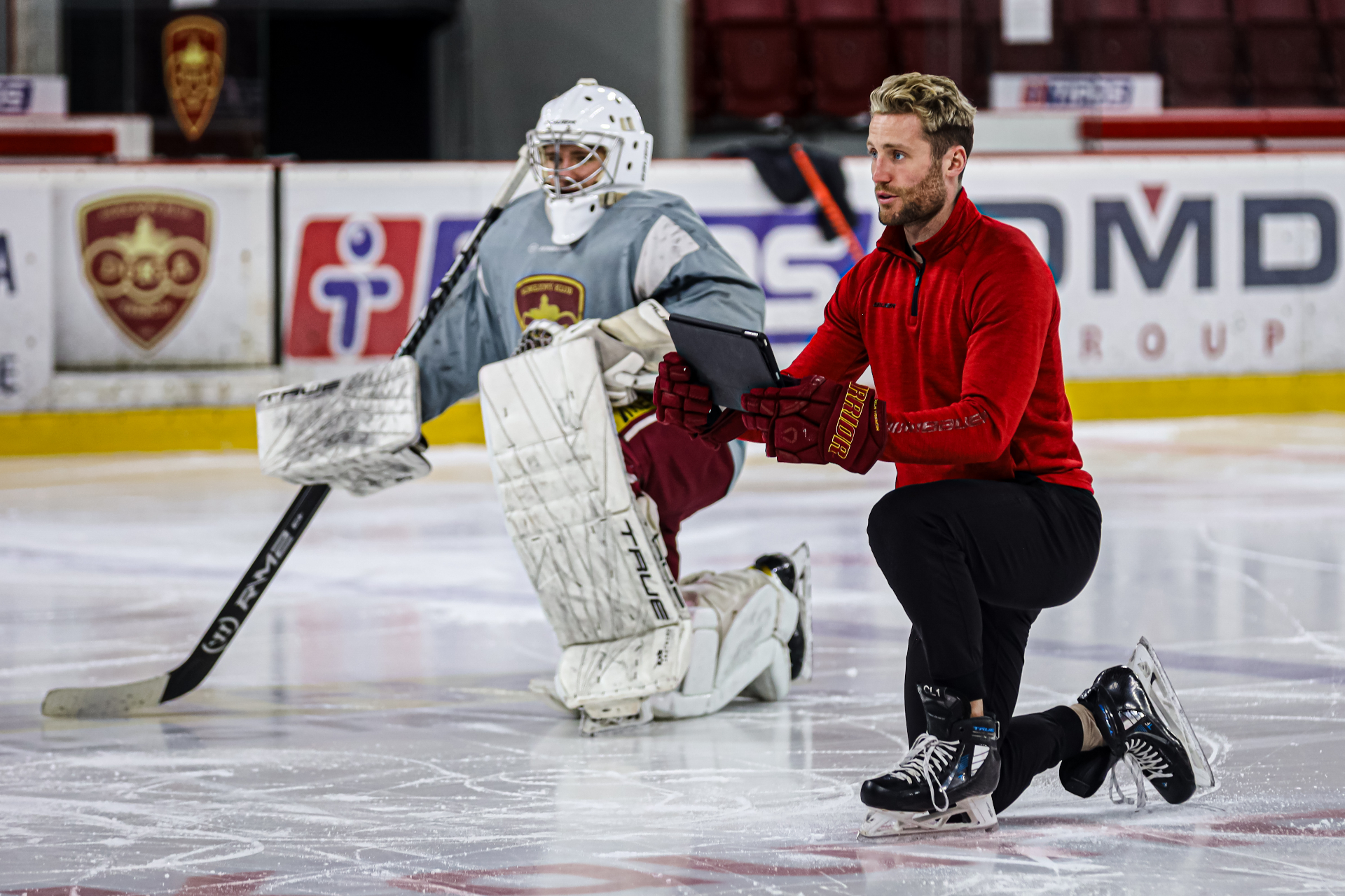Connor LaCouvee coaching a goalie on the ice with iPad
